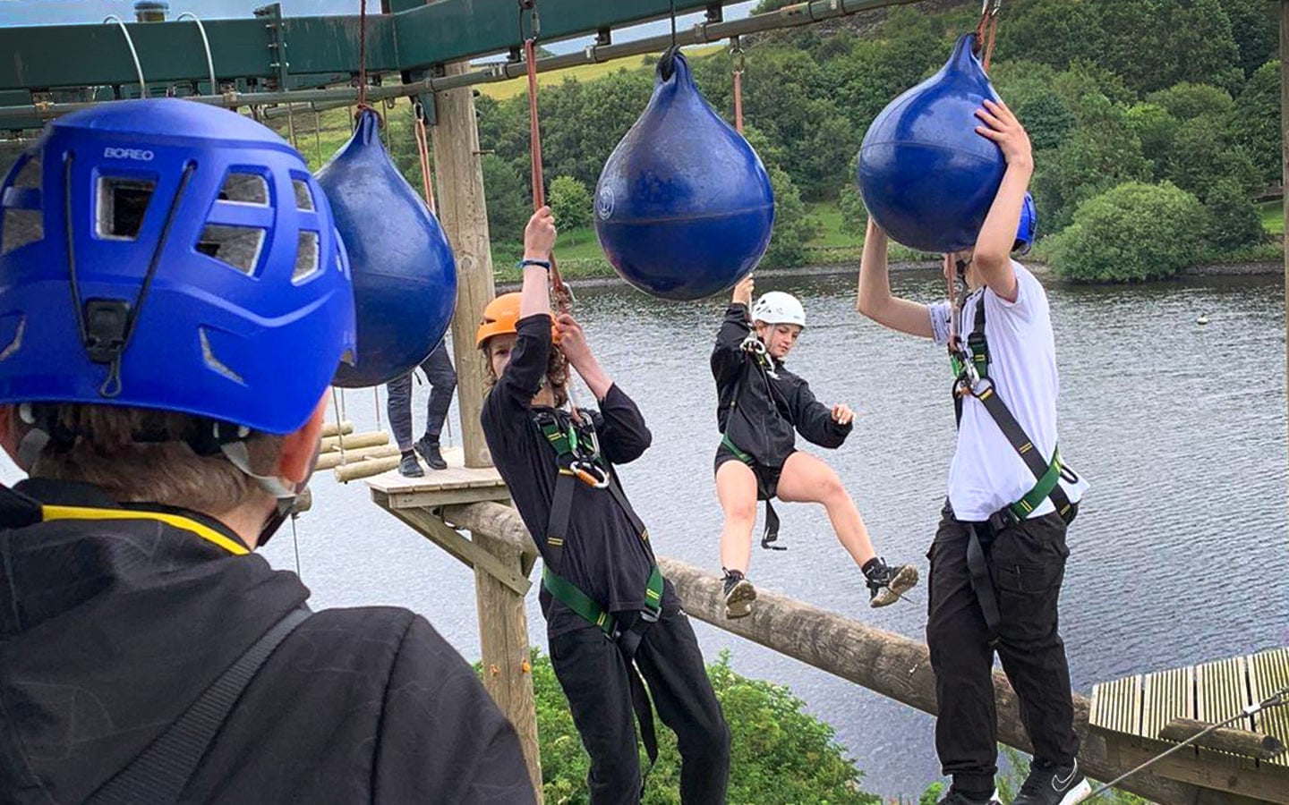 Young people in wetsuits and helmets taking part in watersports at an outdoor activity centre