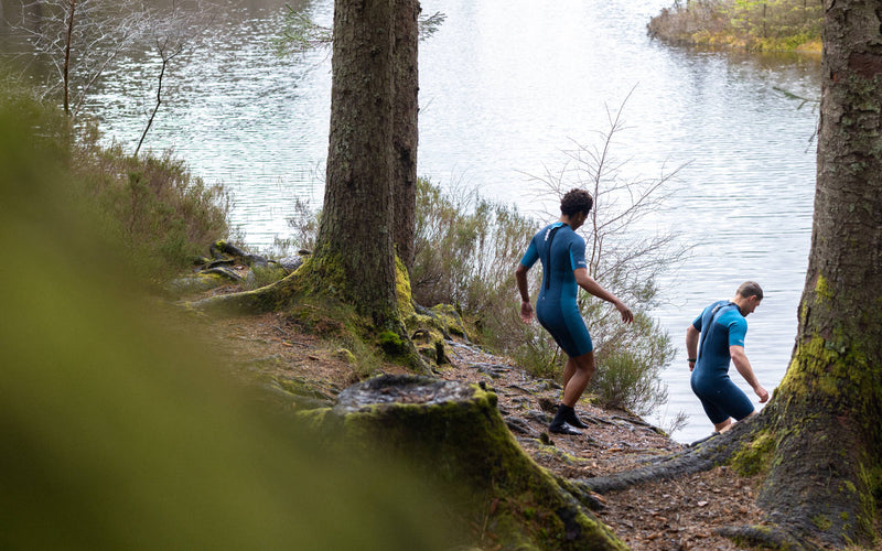 Outdoor swimmers entering the water in wetsuits