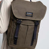 A male model is wearing the Trakke Bannoch Backpack in the Olive colourway. This version has the AustriAlpin COBRA clips on the backpack.